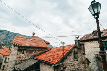 Obraz premium Landscape in Montenegro. Top view of Kotor old townn. Narrow streets with old masonry buildings with small windows, cherished roofs and vintage lamppost against the backdrop of green mountains.
