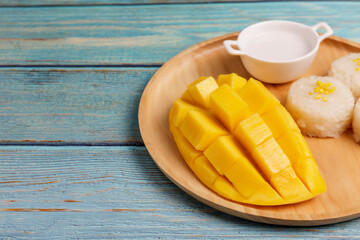 Yellow half  mango with small fork. Mango fruit cubes on the Blue wooden table. Tropical fruit asia. Fresh yellow mango peel and Sliced cubes on wood butcher. Dessert fruit. summer concept.