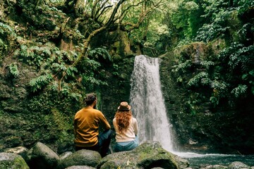 Rear view of couple sitting at a waterfall on Sao Miguel Island, Azores, Portugal
