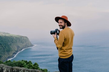 Smiling man with a camera at the coast on Sao Miguel Island, Azores, Portugal
