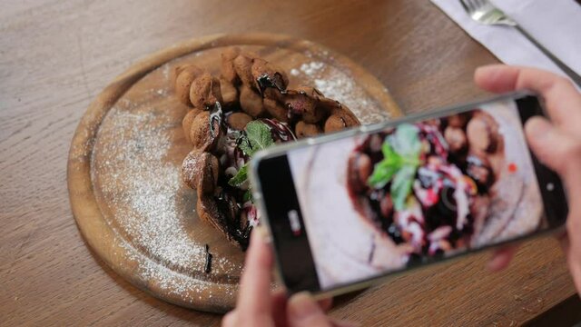 Close-up of hands taking pictures of Hong Kong waffles on a smartphone camera
