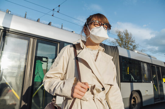 Woman wearing face mask getting off the bus in the city