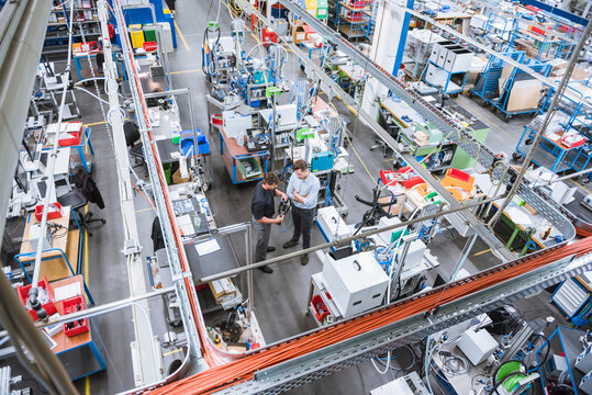 Two Men Having A Meeting In Factory Examining Product