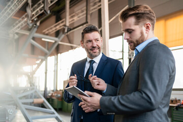 Two businessmen with tablet having a meeting in a factory