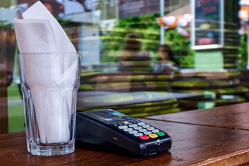 glass of wine, white napkin in a glass, payment card terminal, table in a restaurant,  reflection in the window, bank, banking,  money, electronic, paying, payment, credit, card,