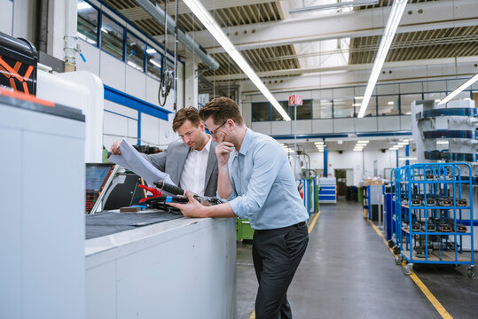Two businessmen discussing a plan in a factory