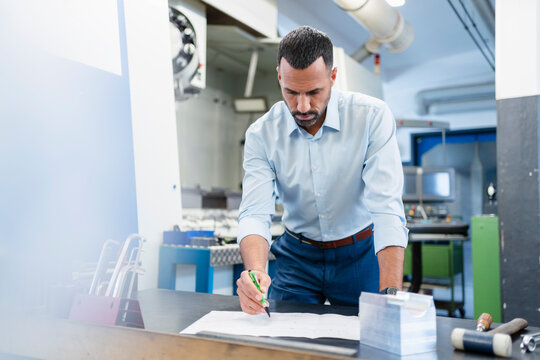 Businessman working on a plan in factory hall