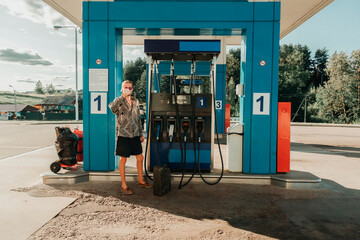 Hitchhiker in sunglasses drinking water on the rural blue filling station of Russia on a sunny day. Horizontal image.