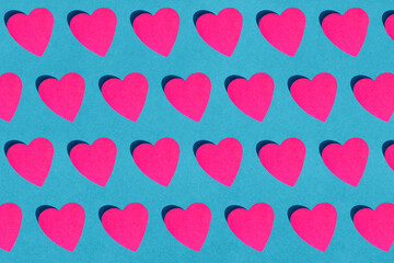 Seamless pattern of pink paper hearts against blue background