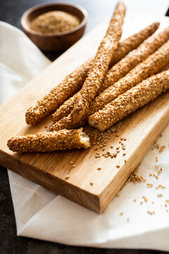 Cutting board and fresh Italian?grissini?breadsticks?with sesame seeds