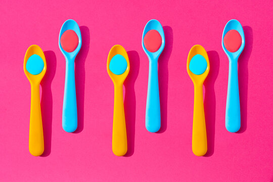 Pattern of yellow and blue plastic teaspoons with blue and red liquid