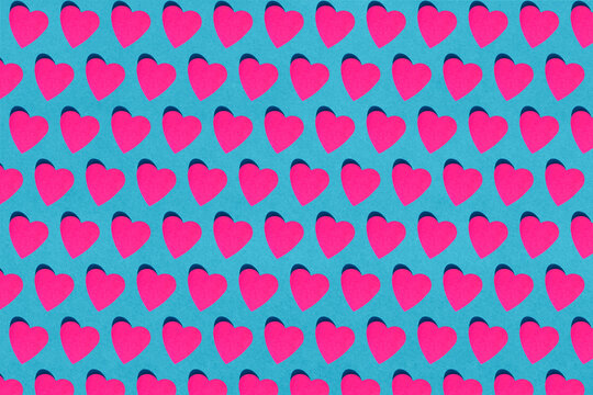 Seamless pattern of pink paper hearts against blue background