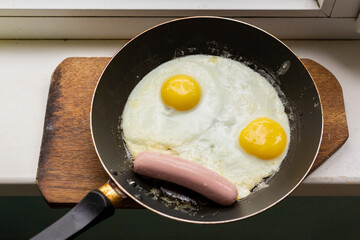 Fried eggs with sausage in a pan