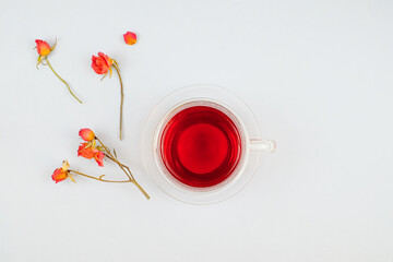 Glass cup of tea and roses on white background top view with copy space