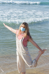 Fototapeta na wymiar a woman doing a pose on the beach with a face mask