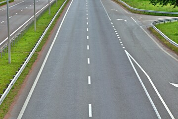 highway with markings and fences without vehicles through the green zone with blurred focus in the background