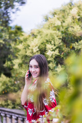Naklejka premium Smiling young woman with red dress making a call outdoor and looking at the camera