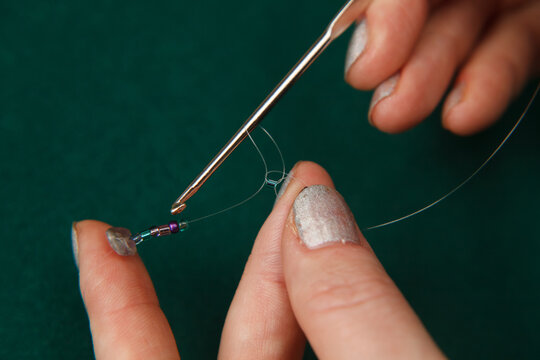 hands stringing beads on a string. needlework