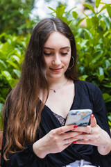 Beautiful young woman using smart phone in the park