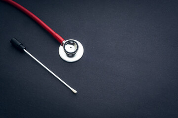 Medical swab and stethoscope closeup on black background. Health care and copy space concept