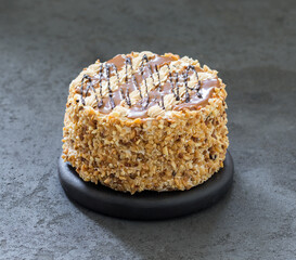 Cake with cream, caramel, nuts and chocolate on a dark background 