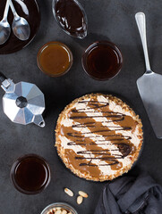 Cake with cream, caramel, nuts and chocolate and coffee on a dark background top view 