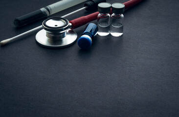 Medical swab, vials and stethoscope closeup on black background. Health care and copy space concept