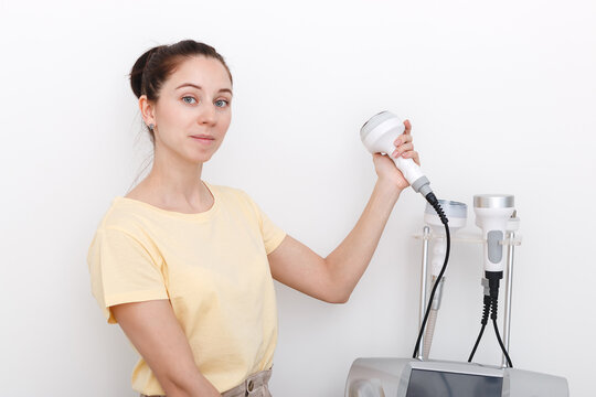 A beautiful woman cosmetologist is holding a bipolar and tripolar nozzle in her hands from a vacuum cavitation apparatus and RF lifting.