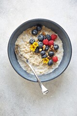 Overnight oatmeal porridge with fresh berries and edible flowers. Top view