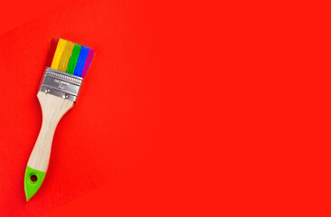 brush with rainbow color bristles on a red background. top view. free space for text. High quality photo