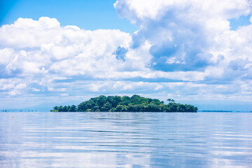 Little Green Tropical Island on clear blue water. Solentiname Archipelago, Nicaragua. Beautiful background peaceful landscape. Virgin Rain forest. View from the boat.