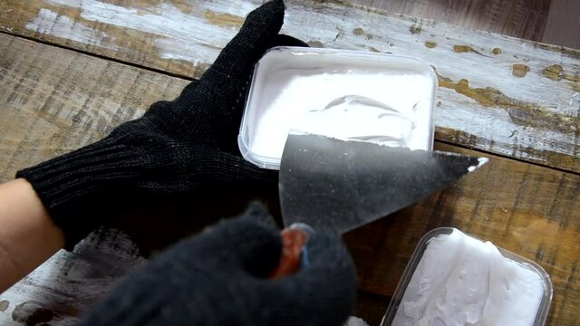 Hands of an old manual worker with wall plastering tools renovating house. Plasterer renovating outdoor walls and corners with spatula and plaster. Wall insulation. Construction finishing works - Imag