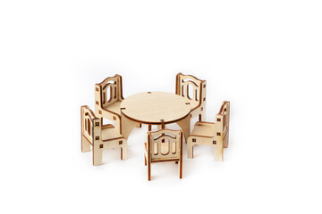 A toy miniature wooden furniture set stands. Dining table and four chairs. Furniture for dolls and dollhouse.