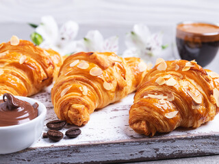 Yummy freshly three croissants sliced almonds with coffee and chocolate paste