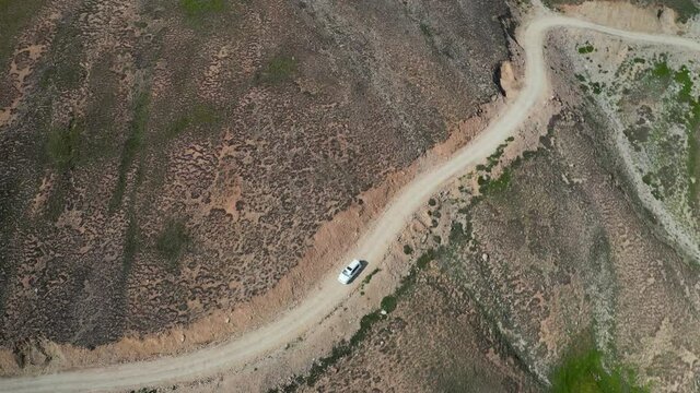 Aerial top view of car driving on a cliff through narrow road
