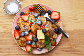 Little pancakes called poffertjes with strawberries, blueberries and colourful candies. 