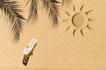 Aerial view of one sunbed, lounge, flip flops, shadow of a palm tree branch draw sun on private sandy beach. Summer and travel concept. Minimalism