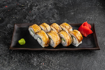 delicious rolls with tuna, avocado, cheese, caviar and eel are placed on a black stone plate and covered with soy sauce
