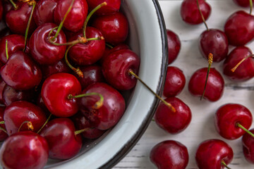 Scattered berries of ripe cherries on a light wooden background and in a bowl. Top view. Seasonal Vitamins.