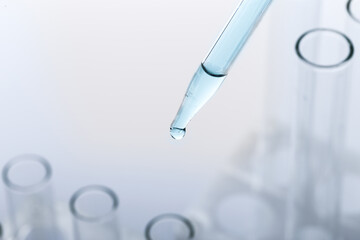 pipette with a drop and scientific laboratory test tubes in a research laboratory.