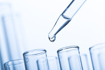 pipette with a drop and scientific laboratory test tubes in a research laboratory.