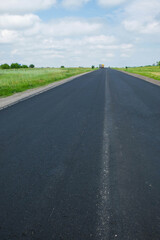 New black asphalt. There is no road marking. Reconstruction of the road in Ukraine on a hot day. Copy space. Vertical image.