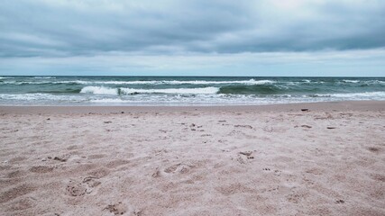 Obraz premium Cloudy rainy day at Baltic Sea. Beautiful sand beach with soft wave in sea water