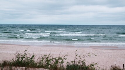 Fototapeta na wymiar Cloudy rainy day at Baltic Sea. Beautiful sand beach with soft wave in sea water