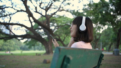 Naklejka premium Tourism concept. An Asian woman is listening to music in the park. 4k Resolution.