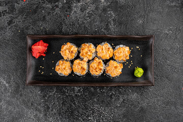 Set of baked sushi rolls with wasabi and ginger on a black background. Japanese oriental cuisine