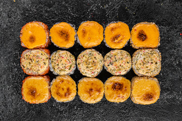 Set of baked sushi rolls with wasabi and ginger on a black background. Japanese oriental cuisine