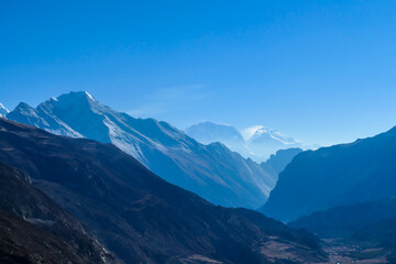 View on high Himalayas along Annapurna Circuit Trek, Nepal. Harsh and barren landscape around. Clear and blue sky. High Himalayan ranges around. Snow capped mountains. Serenity and calmness