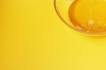 Close-up honey in a glass plate on a yellow background. Health and summer concept. Copy space.