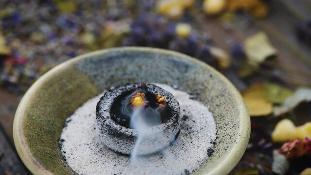 Weihrauch verbrennt blubbernd auf einer Räucherkohle in einem Räuchergefäß, der Rauch wird vom Wind verwirbelt- Räucherritual